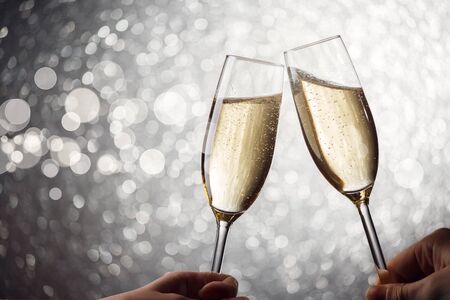 Photo of two wine glasses with wine on gray background, human hands, glitter effectの写真素材