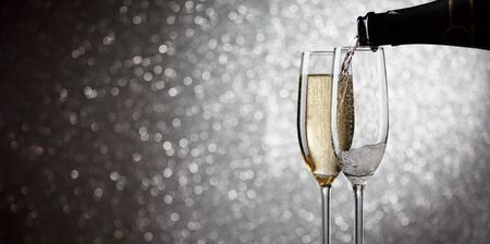 Photo of bottle with pouring wine in wine glasses on gray background, bokeh effectの写真素材