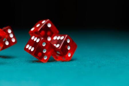 Photo of several red dice falling on green tableの写真素材