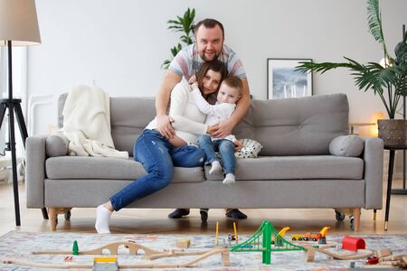 Photo of hugging family with son on gray sofa