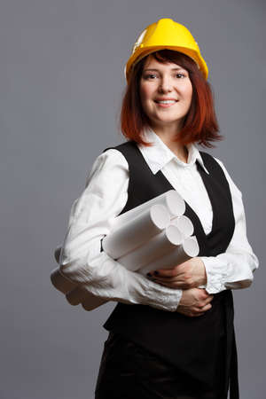 Construction worker in yellow helmet with drawings in rollsの写真素材