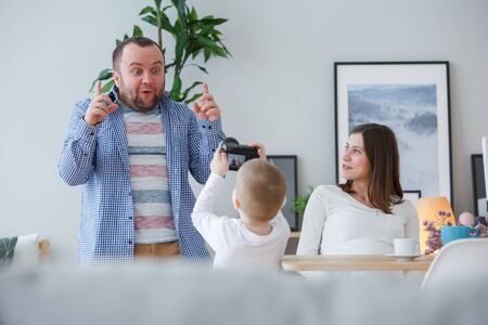 Picture of young son photographing father, mother sitting at tableの写真素材