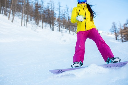 Picture of athlete girl in helmet and mask snowboarding from snowy slope with treesの写真素材