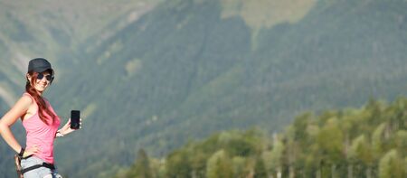 Girl in sunglasses with phone on background of mountainsの写真素材