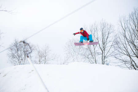 Image of sportive male snowboarder jumping on snowy hillの写真素材