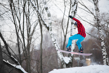 Image of sportsman wearing helmet riding snowboard from snowy slopeの写真素材