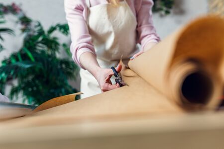 Female florist cutting wrapping paper with scissors for bouquetの写真素材