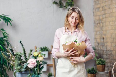 Photo of florist woman in apron with bouquet with kraft paperの写真素材