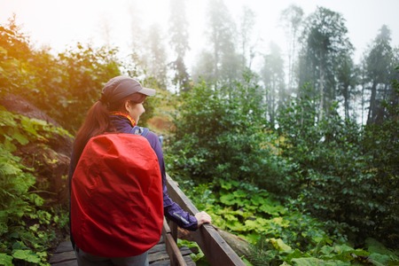 Photo of girl from back with backpack on bridge