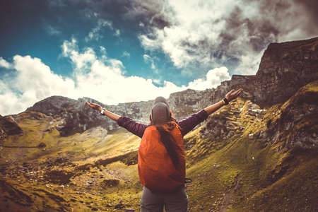 Photo of woman with backpack against background of picturesque mountain landscape