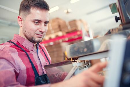 Photo of man graining coffee beans in paper bag