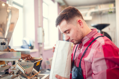 Photo of man sniffing coffee in paper bagの写真素材
