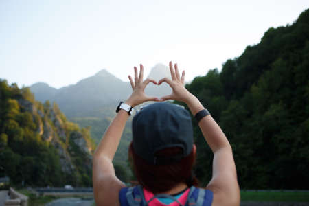 Image from back of female tourist with heart from palmsの写真素材