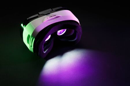Photo of virtual reality glasses with burning pink light on black backgroundの写真素材