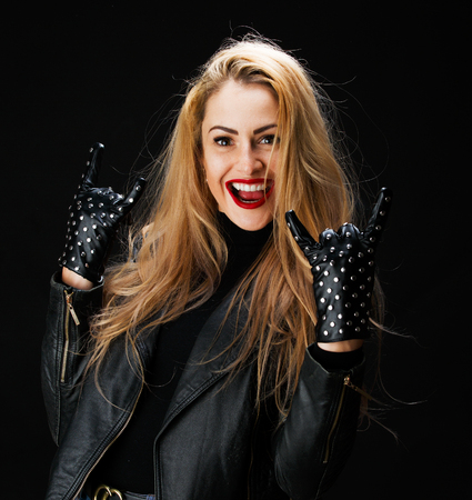 Photo of young blonde in leather jacket showing goat gestureの写真素材