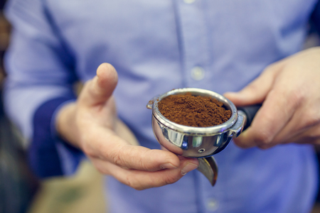 Photo of barista man with ground coffee in handsの写真素材