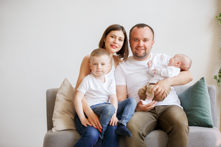 Picture of smiling parents with two young sons sitting on sofaの写真素材