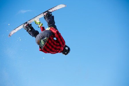 Photo from below of jumping man with snowboard and blue clear skyの写真素材
