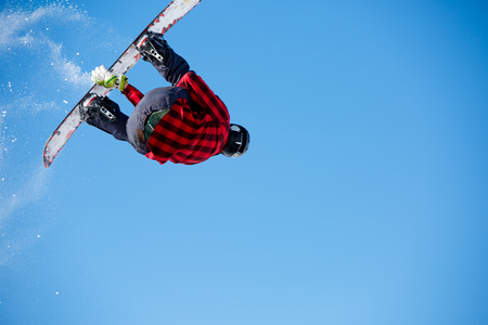 Image from below of jumping man with snowboard and blue clear skyの写真素材
