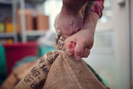 Photo of hands of man holding heavy canvas bagsの写真素材