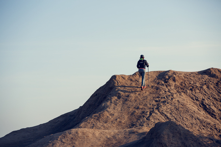 Full-length photo from back of woman growing tourist with backpack and walking sticks on mountainの写真素材