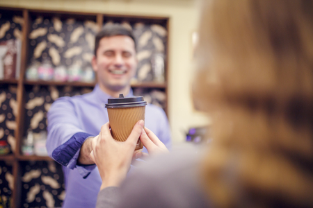 Photo of barista man stretching glass to woman on blurred background.の写真素材