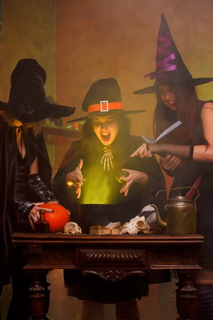 Three witches boiling potion in cauldronの写真素材