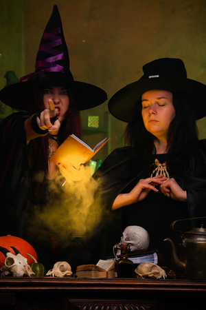 Two witches in black hats making potionsの写真素材