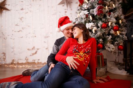 Loving man and pregnant woman on background of Christmas decorationsの写真素材