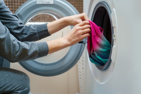 Photo of woman folding clothes into washing machineの写真素材