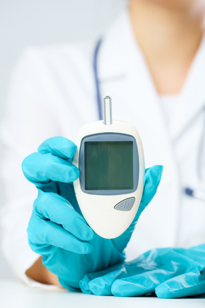 Image of doctors hand with glucometer.の写真素材