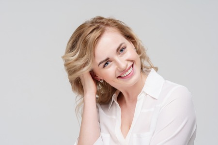 Photo of smiling curly woman in white shirt in studio.の写真素材