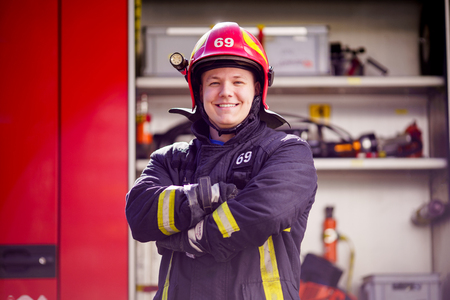Image of happy male firefighter in helmet on background of fire truckの写真素材