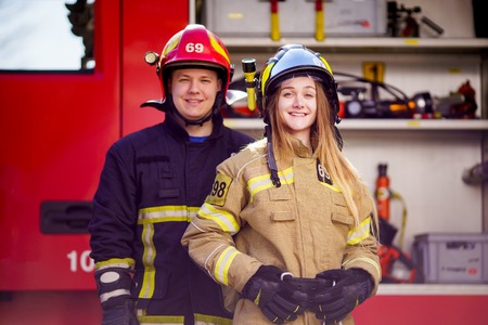 Image of firefighters women and men in helmets looking at camera near fire truckの写真素材
