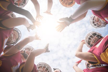 Image from below of team of American football players against blue skyの写真素材
