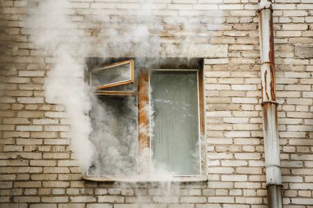 Picture of brick house with smoke coming out of window.の写真素材