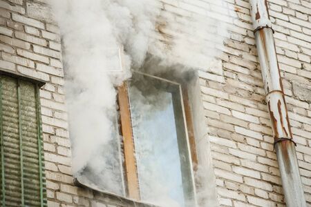 Image of brick house with smoke coming out of windowの写真素材