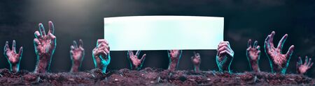 Photo of zombie hands with blank paper sticking out of graveの写真素材