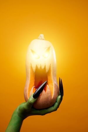 Photo of green zombie hand with pumpkin .の写真素材