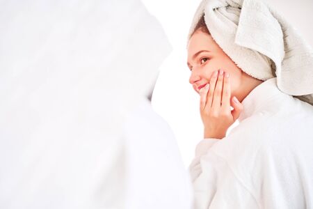 Side photo of woman in white coat and with towel on her headの写真素材