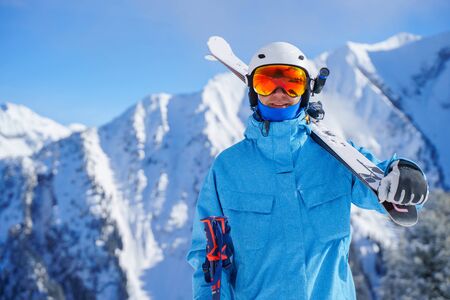 Portrait of man in helmet with skis on snowy resort in winter afternoon