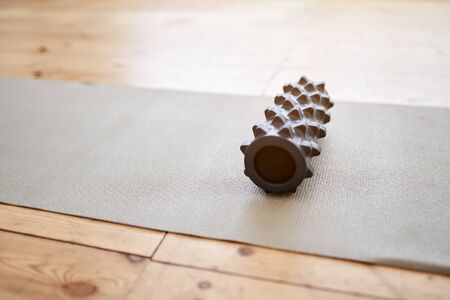 Gray massager with spikes lying on gray rug on wooden floor in gymの写真素材