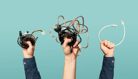 Three hands with some old wires. Concept of electrical waste.