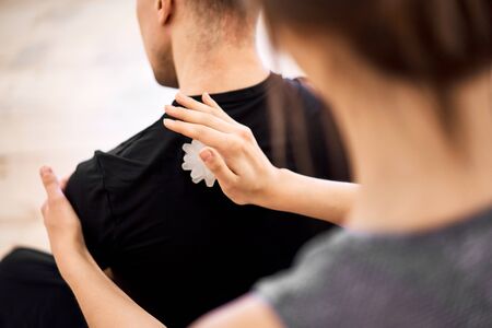 Woman doing back massage to man with massage ball in roomの写真素材
