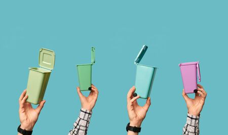 Four hands with plastic trash containers on clean blue background.の写真素材