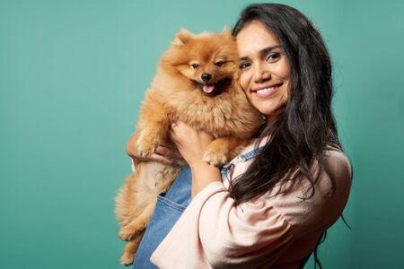 Happy woman with pug on blank blue backgroundの写真素材