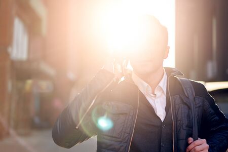 Man talking on phone in city against backdrop of modern buildings.の写真素材