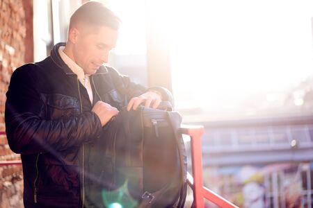 Man with bag on walk in city against backdrop of modern buildings at day.の写真素材
