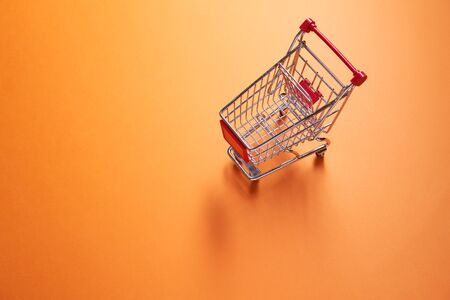 Iron small supermarket trolley on empty orange backgroundの写真素材