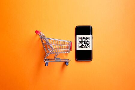 Iron toy trolley with code for reading from supermarket on empty orange backgroundの写真素材